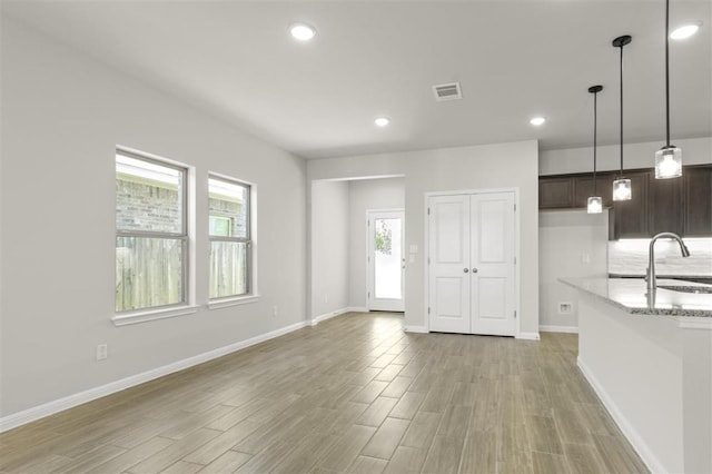 18309 Emu Ln, Manor, TX 78653 - kitchen featuring a sink, light wood finished floors, dark brown cabinets, pendant lighting, and baseboards