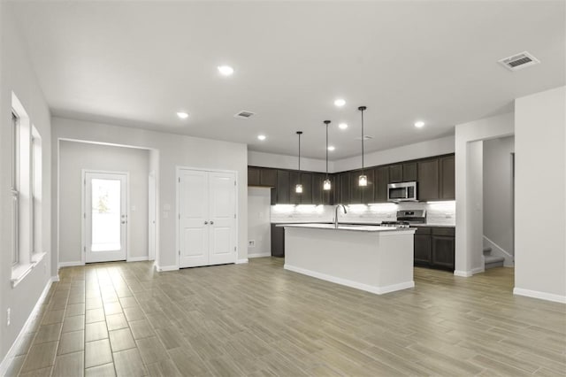 18309 Emu Ln, Manor, TX 78653 - kitchen with appliances with stainless steel finishes, light wood-style floors, baseboards, a center island with sink, and light countertops
