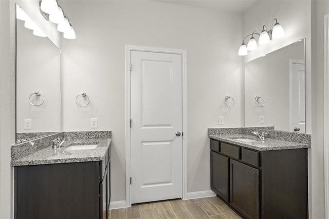 18309 Emu Ln, Manor, TX 78653 - bathroom with two vanities, wood finish floors, and baseboards