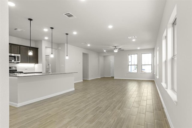 18309 Emu Ln, Manor, TX 78653 - unfurnished living room with baseboards, light wood finished floors, recessed lighting, a ceiling fan, and a sink