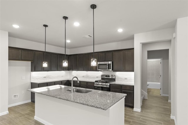 18309 Emu Ln, Manor, TX 78653 - kitchen with stainless steel appliances, a sink, light wood finished floors, dark brown cabinetry, and recessed lighting