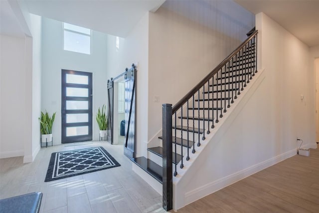 121 Black Talon Ln, Cedar Creek, TX 78612 - foyer entrance with a barn door, baseboards, stairs, a high ceiling, and wood finished floors