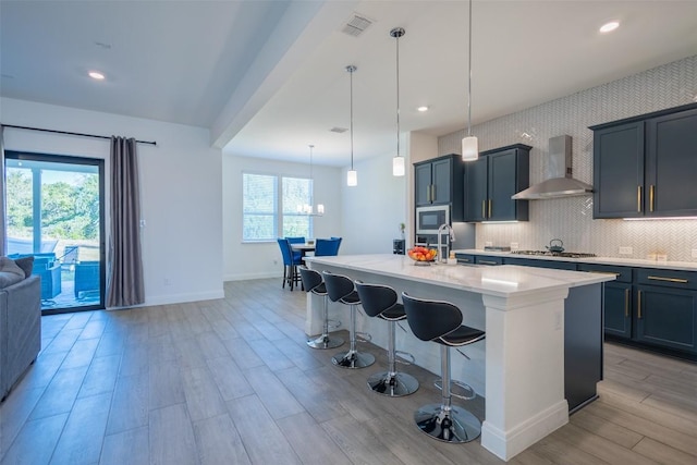 121 Black Talon Ln, Cedar Creek, TX 78612 - kitchen with wall chimney exhaust hood, appliances with stainless steel finishes, light wood finished floors, light countertops, and a kitchen breakfast bar