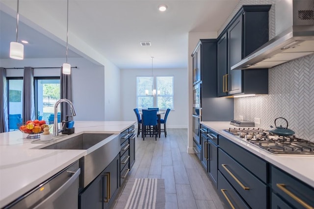 121 Black Talon Ln, Cedar Creek, TX 78612 - kitchen with wall chimney range hood, appliances with stainless steel finishes, backsplash, plenty of natural light, and recessed lighting