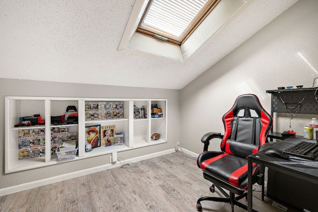 home office featuring baseboards, a textured ceiling, wood finished floors, and vaulted ceiling with skylight