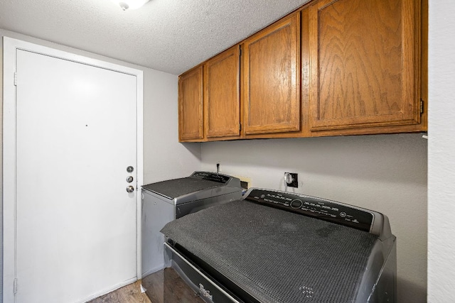 washroom with a textured ceiling, cabinet space, and washer / clothes dryer