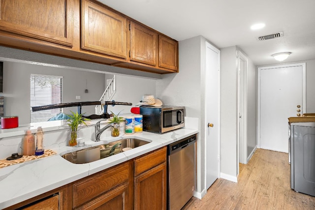 kitchen with light countertops, a sink, visible vents, appliances with stainless steel finishes, and brown cabinetry