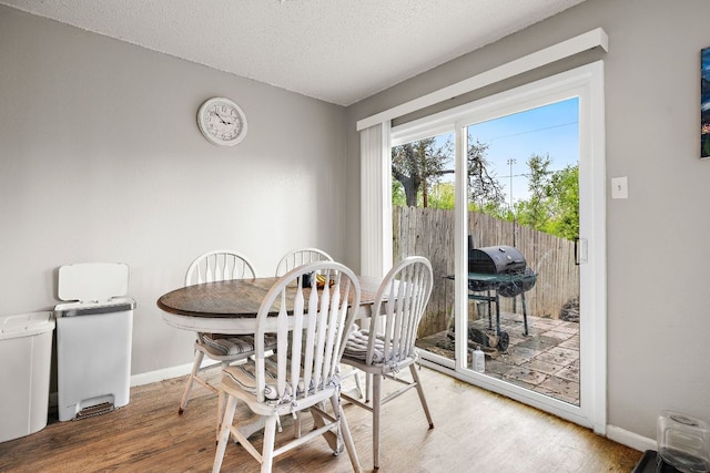 dining space with baseboards, wood finished floors, and a textured ceiling