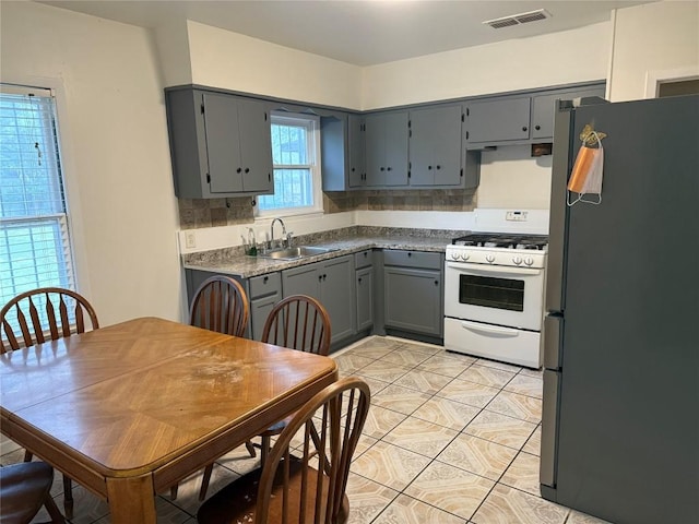 6300 Hickman Ave, Austin, TX 78723 - kitchen featuring freestanding refrigerator, white range with gas cooktop, gray cabinetry, and light tile patterned floors