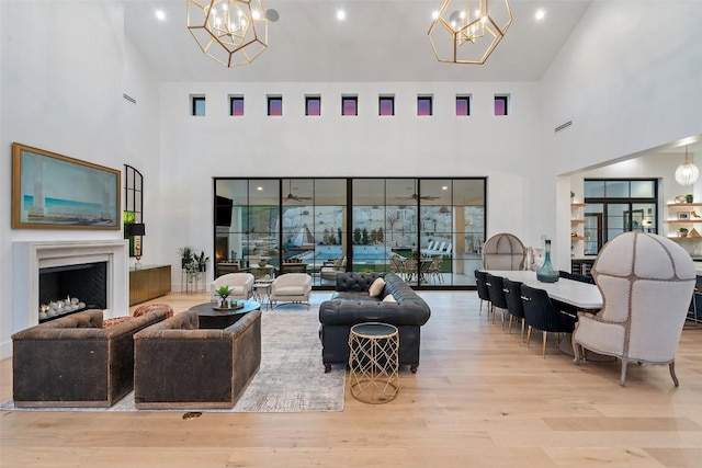 living area featuring wood finished floors, a towering ceiling, a fireplace, and a chandelier