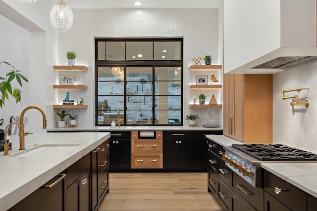 kitchen featuring open shelves, stainless steel gas cooktop, a sink, and premium range hood