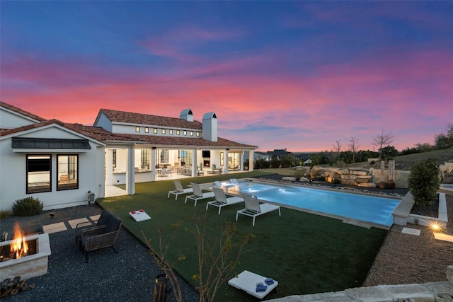 outdoor pool with an outdoor living space with a fire pit, a yard, and a patio