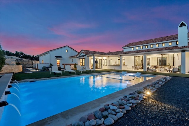 pool at dusk featuring an outdoor pool, an outdoor hangout area, and a patio