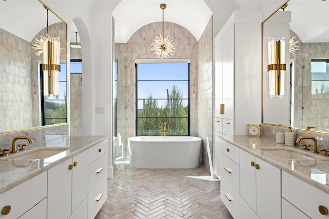 bathroom featuring two vanities, a soaking tub, a sink, and a chandelier