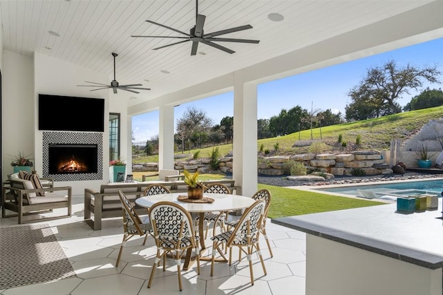 view of patio featuring an outdoor living space with a fireplace, a ceiling fan, and outdoor dining space