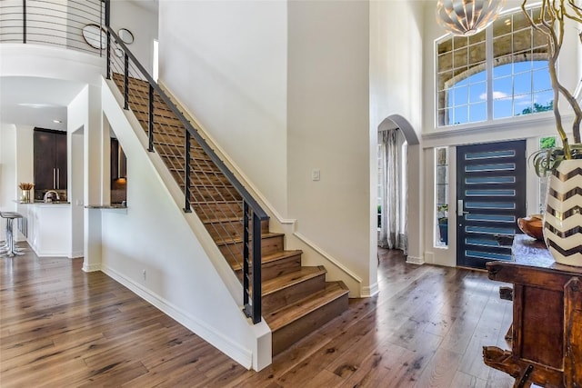 5802 Gentle Breeze Ter, Austin, TX 78731 - entrance foyer featuring a towering ceiling, arched walkways, stairway, wood-type flooring, and a chandelier