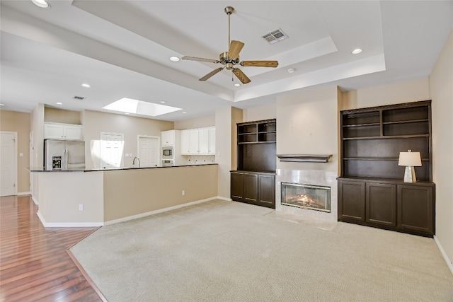 6407 Johanne Ct, Austin, TX 78750 - unfurnished living room with a skylight, a raised ceiling, recessed lighting, ceiling fan, and a premium fireplace