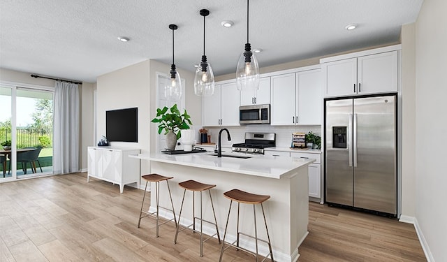 513 Raleigh Dr, Georgetown, TX 78633 - kitchen featuring appliances with stainless steel finishes, a sink, light wood-style floors, light countertops, and a center island with sink