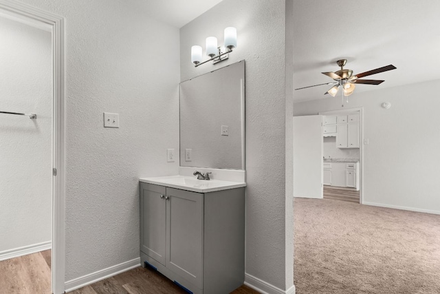 bathroom featuring baseboards, vanity, a textured wall, and a ceiling fan