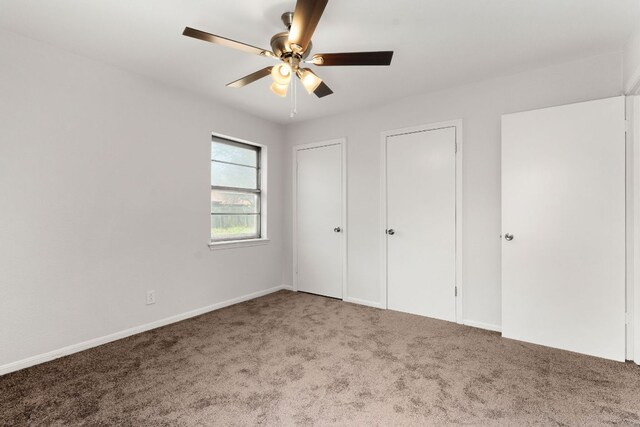 unfurnished bedroom featuring carpet flooring, ceiling fan, and multiple closets