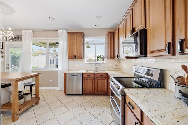 105 Wimberley St, Hutto, TX 78634 - kitchen with stainless steel appliances, a sink, brown cabinetry, healthy amount of natural light, and recessed lighting