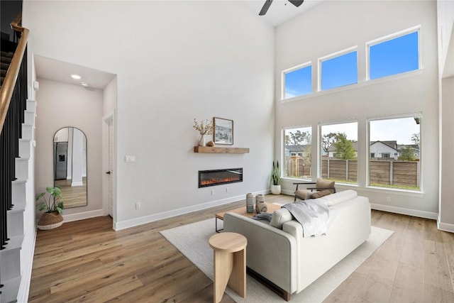 1017 Dog Iron St, Georgetown, TX 78633 - living area with a towering ceiling, a glass covered fireplace, stairs, a ceiling fan, and light wood-type flooring
