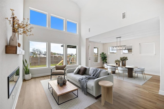1017 Dog Iron St, Georgetown, TX 78633 - living room with light wood-type flooring, a high ceiling, and a glass covered fireplace