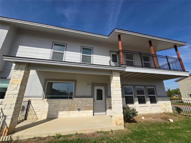 2105 Tiger Trl Unit 501, Round Rock, TX 78665 - view of front of house featuring stone siding, a balcony, stucco siding, and fence