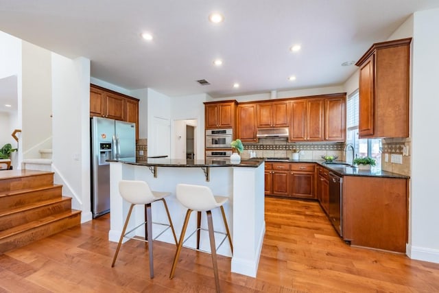 7724 Yaupon Dr, Austin, TX 78759 - kitchen with appliances with stainless steel finishes, under cabinet range hood, a sink, brown cabinets, and tasteful backsplash