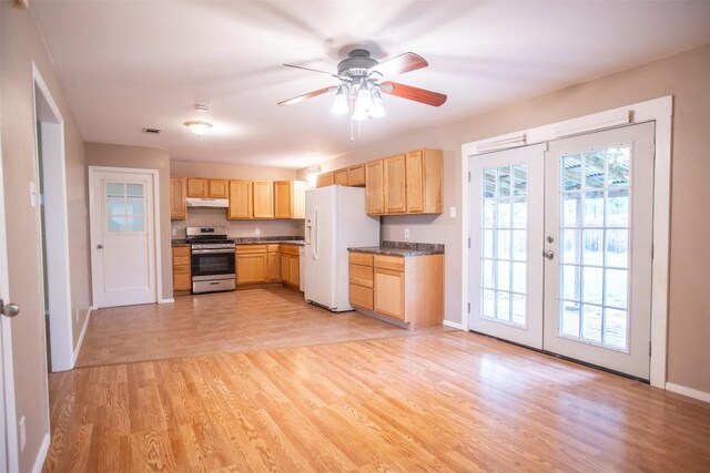 2312 Devonshire Dr, Austin, TX 78723 - kitchen featuring stainless steel gas stove, white fridge with ice dispenser, under cabinet range hood, dark countertops, and french doors