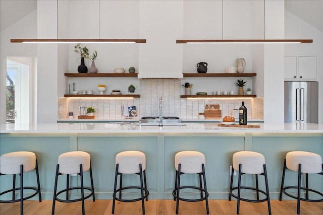 13400 Paisano Trl, Austin, TX 78737 - kitchen featuring high quality fridge, open shelves, white cabinets, a kitchen bar, and backsplash
