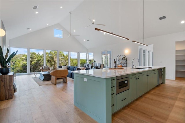 13400 Paisano Trl, Austin, TX 78737 - kitchen with green cabinetry, a sink, high vaulted ceiling, light wood-style floors, and a kitchen island with sink