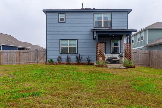 rear view of house featuring a lawn and a fenced backyard