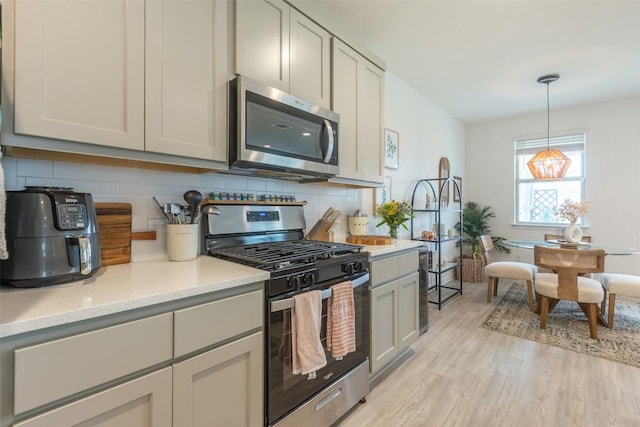 12305 Zenyatta Dr, Buda, TX 78610 - kitchen with backsplash, hanging light fixtures, light stone countertops, light wood-type flooring, and stainless steel appliances
