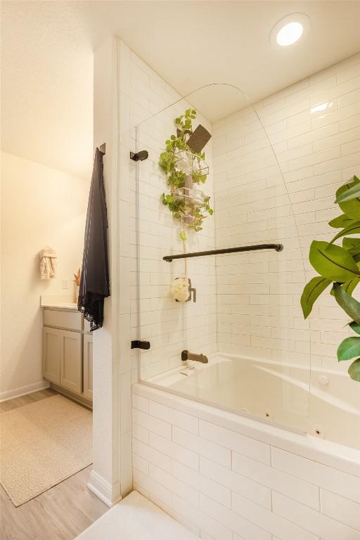12305 Zenyatta Dr, Buda, TX 78610 - bathroom with wood finished floors, baseboards, a combined bath / shower with jetted tub, and vanity