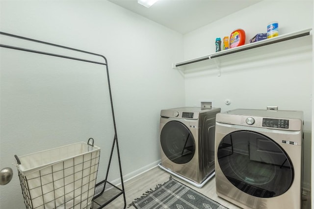 laundry room featuring washing machine and clothes dryer, laundry area, baseboards, and light wood-style floors
