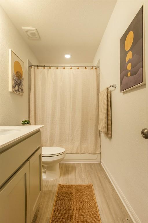 12305 Zenyatta Dr, Buda, TX 78610 - full bathroom with visible vents, wood finished floors, vanity, toilet, and shower / tub combo with curtain