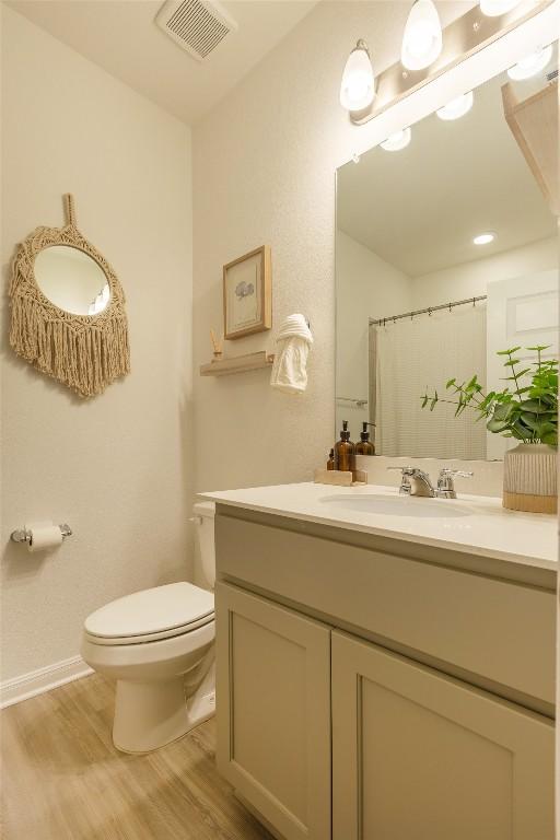 12305 Zenyatta Dr, Buda, TX 78610 - full bath featuring visible vents, vanity, wood finished floors, toilet, and baseboards