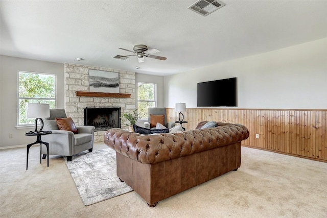 591 Young Ranch Rd, Georgetown, TX 78633 - living area with light carpet, a ceiling fan, a wainscoted wall, a stone fireplace, and wooden walls