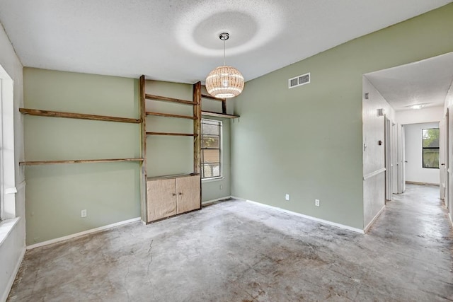 2511 Bitter Creek Dr, Austin, TX 78744 - spare room with concrete floors, a chandelier, baseboards, and a textured ceiling