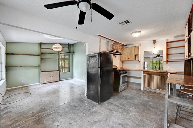 2511 Bitter Creek Dr, Austin, TX 78744 - kitchen featuring freestanding refrigerator, stainless steel range with gas stovetop, ceiling fan, open shelves, and baseboards