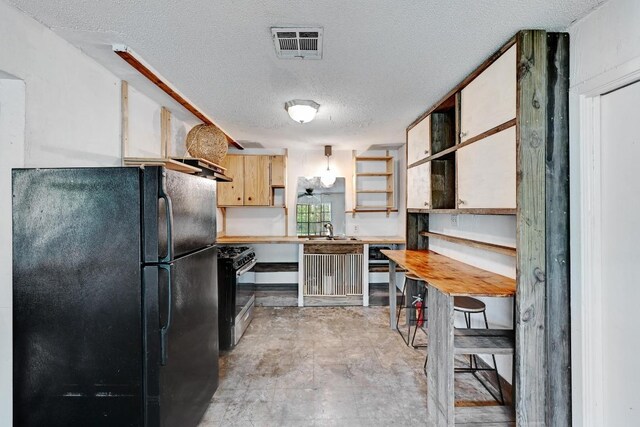 2511 Bitter Creek Dr, Austin, TX 78744 - kitchen with freestanding refrigerator, gas stove, a sink, a textured ceiling, and open shelves