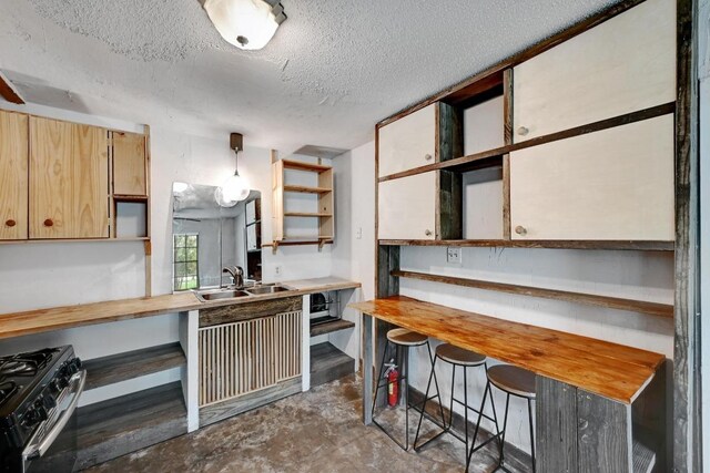 2511 Bitter Creek Dr, Austin, TX 78744 - kitchen with open shelves, a sink, range with gas cooktop, concrete flooring, and a textured ceiling