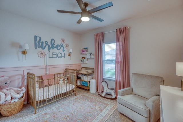 312 Heatherwood Ter, Marble Falls, TX 78654 - bedroom with a wainscoted wall, a crib, a decorative wall, and a ceiling fan