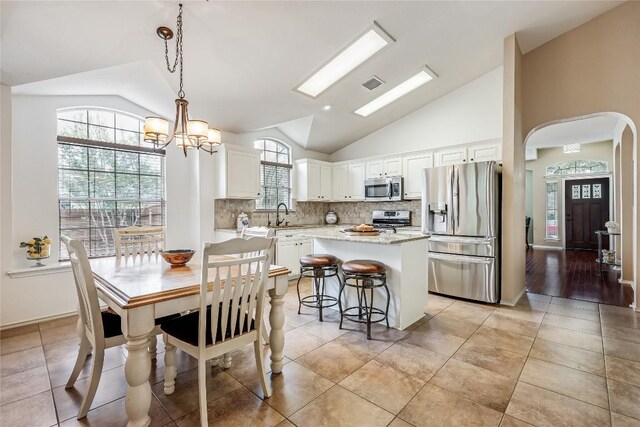 14516 Wharton Park Trl, Austin, TX 78717 - dining space featuring lofted ceiling, arched walkways, a chandelier, and light tile patterned flooring