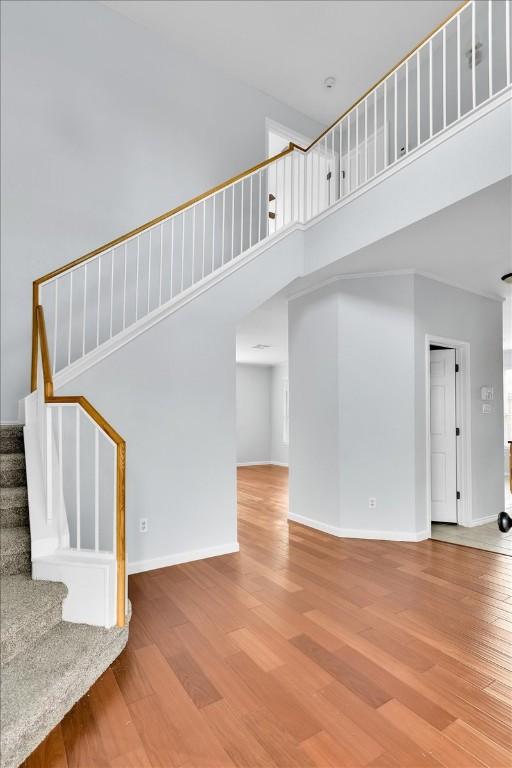 16101 Mcdows Hole Ln, Austin, TX 78717 - unfurnished living room with a towering ceiling, wood finished floors, stairs, and baseboards