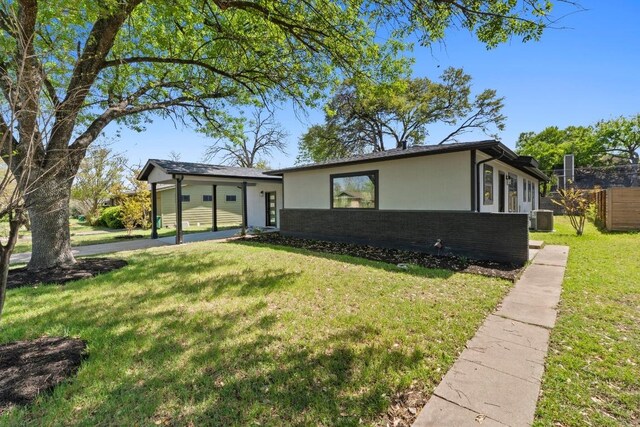mid-century home with driveway, stucco siding, brick siding, a front lawn, and central AC