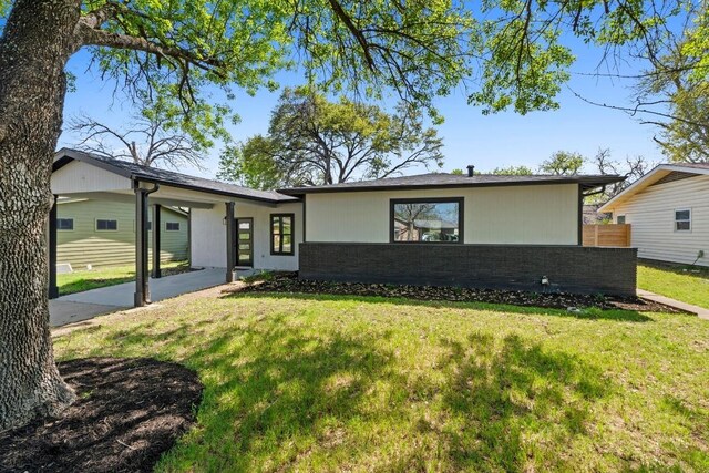 view of front facade featuring brick siding, fence, a front yard, and a carport