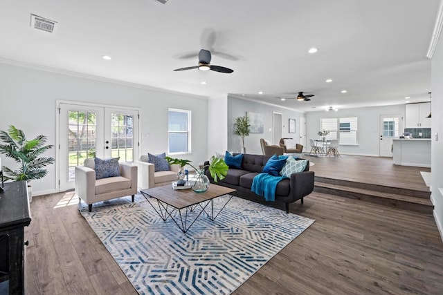 living area featuring a wealth of natural light, wood finished floors, ornamental molding, and a ceiling fan