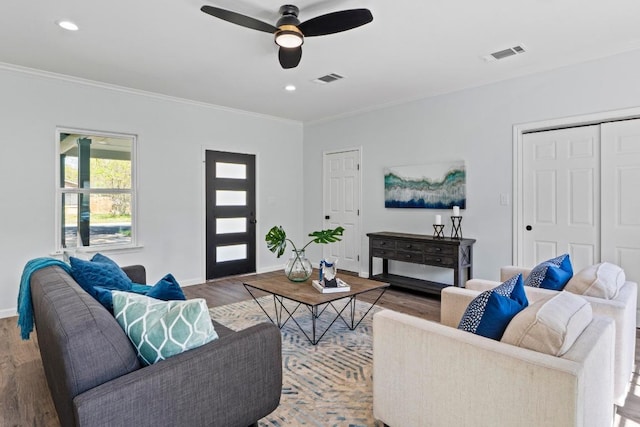 living room with wood finished floors, ornamental molding, baseboards, and ceiling fan
